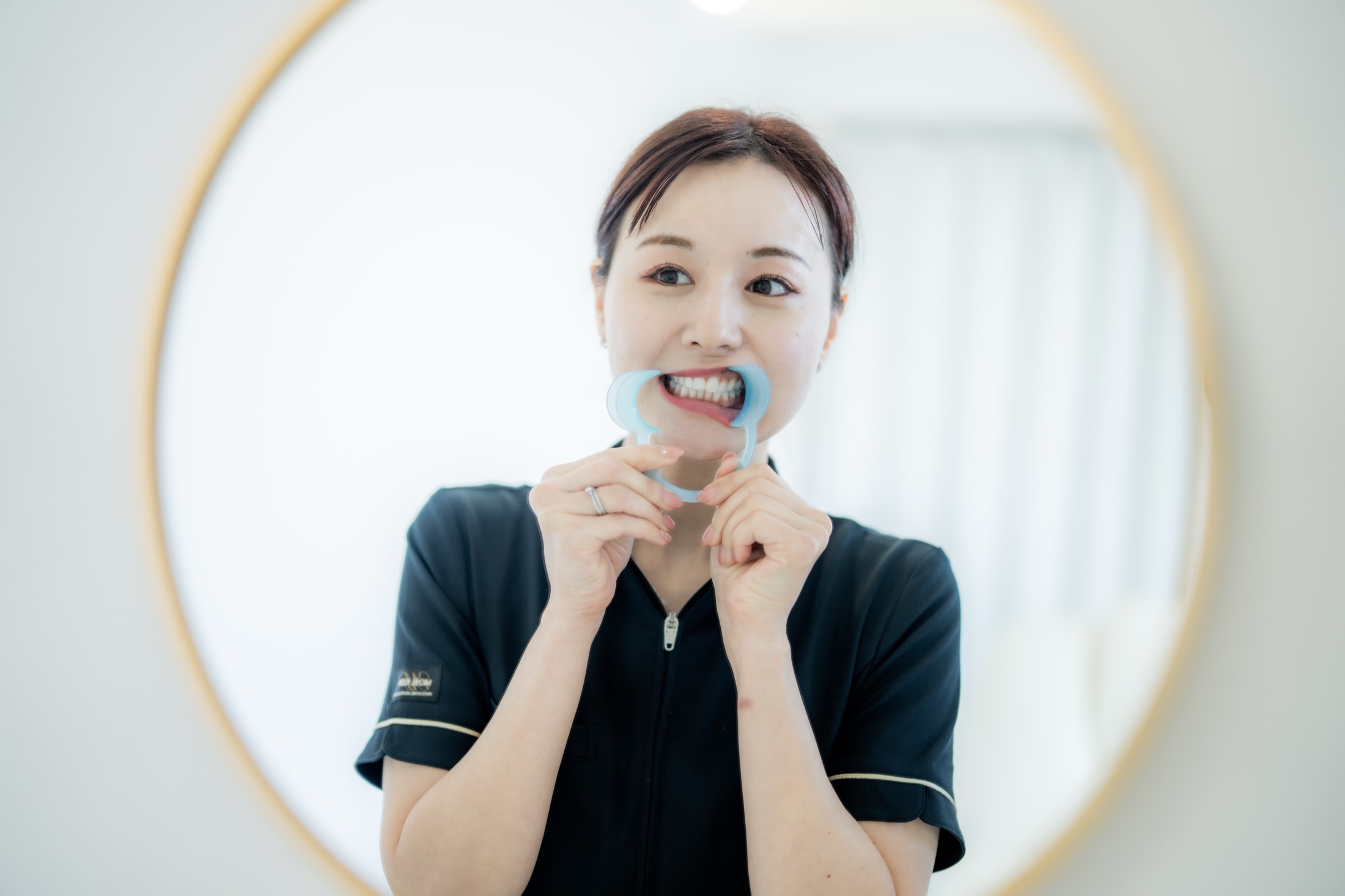 鏡の前でセルフホワイトニングのマウスピースを装着する女性